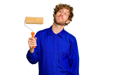 Young painter man holding a roll isolated on white background dreaming of achieving goals and purposes