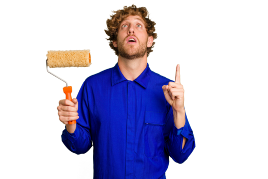 Young painter man holding a roll isolated on white background pointing upside with opened mouth.