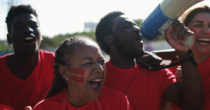 African red sport fans screaming while supporting their team - Football supporters having fun at competion event - Champions and winning concept 