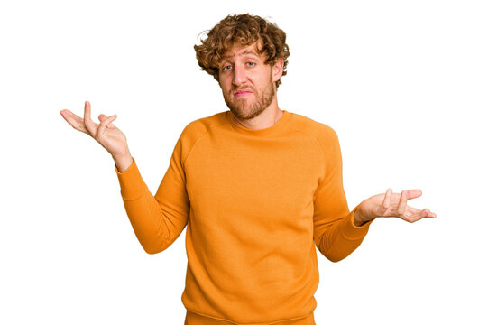 Young caucasian man isolated on green chroma background doubting and shrugging shoulders in questioning gesture.