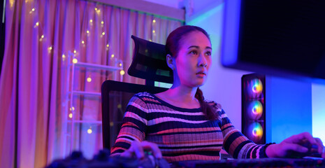 Obraz premium An active and serious young woman gamer on his powerful personal computer, playing first-person online video games.
