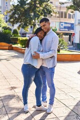 Young latin couple expecting baby hugging each other standing at park