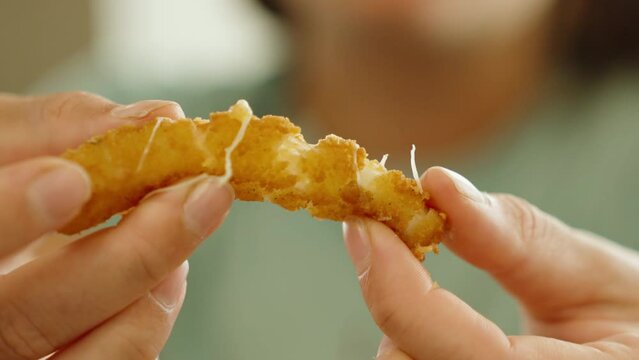 The girl breaks a cheese stick and the cheese stretches out of it, close-up, slow motion.