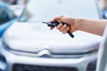 Young caucasian man opening car with automatic key at street