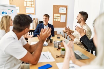 Group of young business workers smiling and clapping to partner at the office.