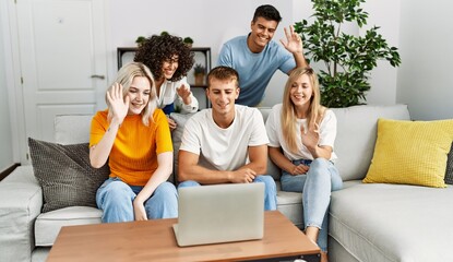 Fototapeta premium Group of young friends smiling happy having video call using laptop at home.