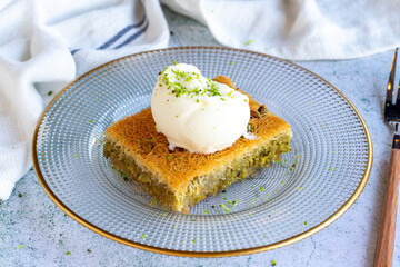 Pistachio Kadaif dessert. Traditional Mediterranean cuisine delicacies. Kadayif dessert with ice cream on gray background. close up