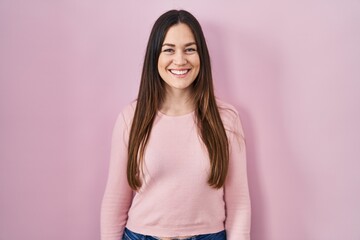 Fototapeta premium Young brunette woman standing over pink background with a happy and cool smile on face. lucky person.
