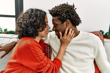 Young interracial romantic couple sitting on the sofa by at home.