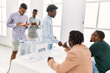 Group of young african american voter people putting vote in ballot standing at electoral center.