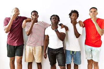 Young african group of friends standing together over isolated background bored yawning tired covering mouth with hand. restless and sleepiness.