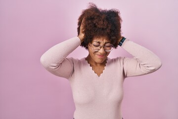 Fototapeta na wymiar Young african american woman standing over pink background suffering from headache desperate and stressed because pain and migraine. hands on head.