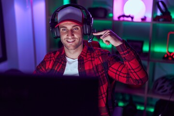 Young caucasian man playing video games smiling happy pointing with hand and finger