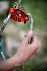 Man's hands operating a rock climbing belaying device