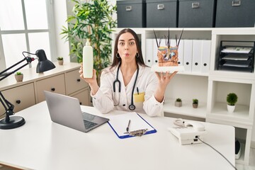 Hispanic doctor woman holding model of human anatomical skin and hair making fish face with mouth and squinting eyes, crazy and comical.