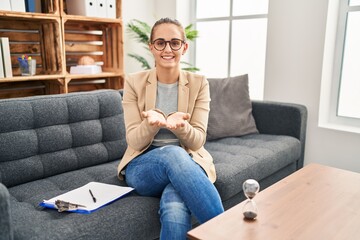 Young woman working at consultation office smiling with hands palms together receiving or giving gesture. hold and protection