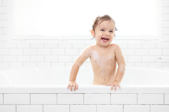 Laughing toddler standing in bathtub