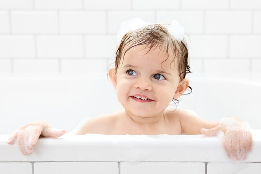 Happy toddler with wet hair in bathtub