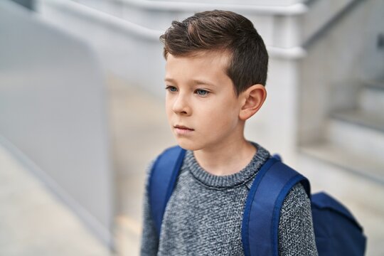 Blond child student standing with serious expression at school