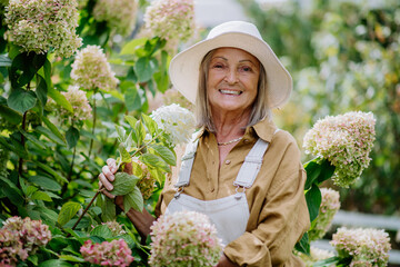 Happy senior woman posing in the flower garden.
