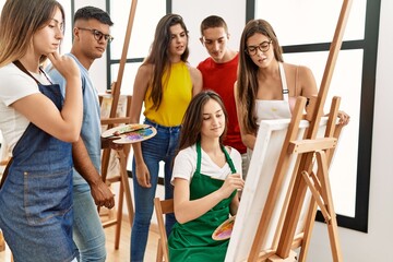 Group of people with serious expression looking draw of partner at art studio.
