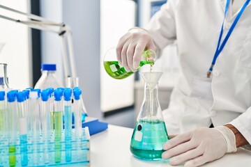 Fototapeta premium Young hispanic man scientist measuring liquid at laboratory