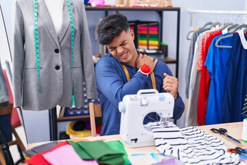 Naklejka na ściany i meble Young hispanic man tailor stressed using sewing machine at clothing factory