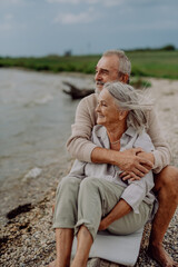 Senior couple sitting and having romantic moment near the autumn sea.