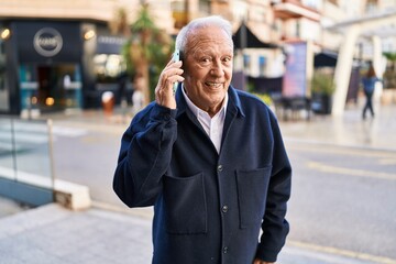 Fototapeta na wymiar Senior man smiling confident talking on the smartphone at street
