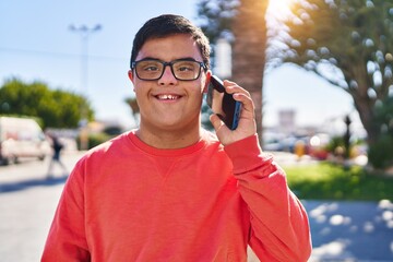 Down syndrome man smiling confident talking on the smartphone at park