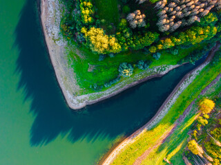 Aerial view of coast of natural lake in autumn with beautiful tree colours and reflections