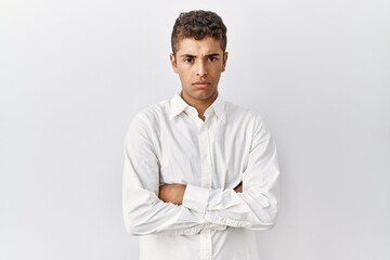Young handsome hispanic man standing over isolated background skeptic and nervous, disapproving...