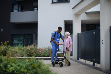 Fototapeta na wymiar Caregiver walking with senior woman client in front of nurishing home.