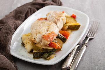Fried fish with baked vegetables on white dish