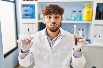 Arab man with beard working at scientist laboratory holding blood sample looking at the camera...