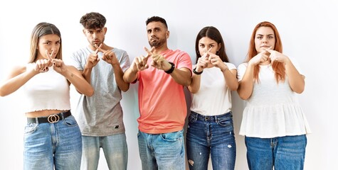 Group of young friends standing together over isolated background rejection expression crossing fingers doing negative sign