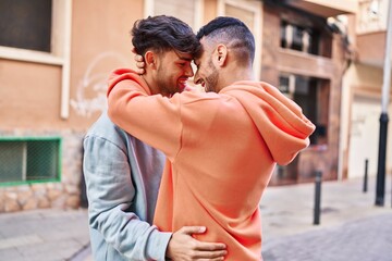 Two man couple hugging each other standing at street