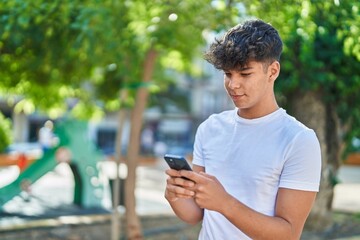 Fototapeta na wymiar Young hispanic teenager smiling confident using smartphone at park