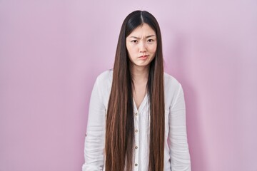 Obraz premium Chinese young woman standing over pink background skeptic and nervous, frowning upset because of problem. negative person.