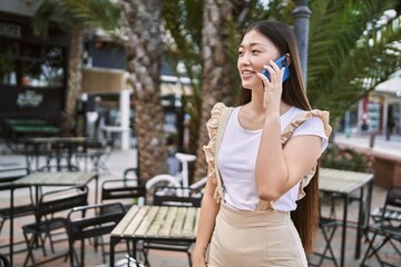 Young chinese girl smiling happy talking on the smartphone at the city.