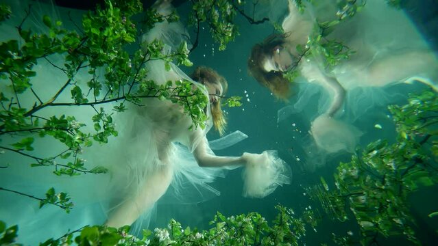 subaquatic slow motion shot in fabulous sea or ocean, princess is floating in depth, reflection in water