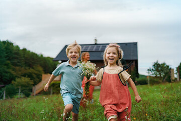Happy family running near their house with solar panels. Alternative energy, saving resources and...