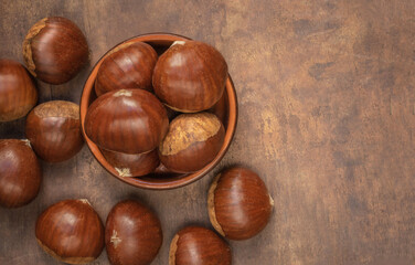 Edible chestnuts on dark rustic background.  Horse chestnuts top view. Flat lay, copy space.