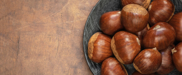 Edible chestnuts on dark rustic background.  Horse chestnuts top view. Flat lay, copy space.