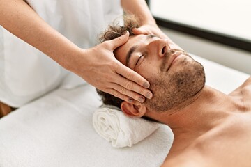 Fototapeta na wymiar Young hispanic man having facial massage at beauty center