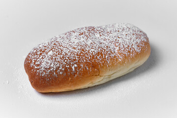 long bun with powdered sugar on white background