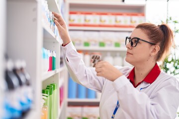 Young beautiful plus size woman pharmacist holding pills tablet on shelving at pharmacy
