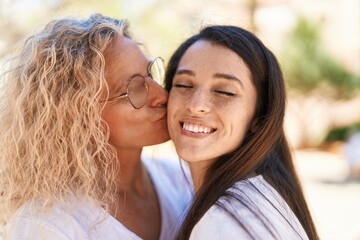 Fototapeta premium Two women mother and daughter standing together kissing at park
