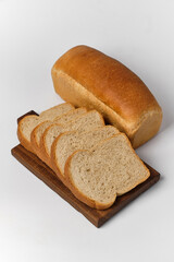 loaf of bread and sliced pieces on a board on a white background