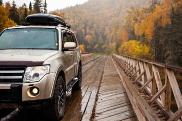 4x4 car on wooden bridge in the forest in autumn